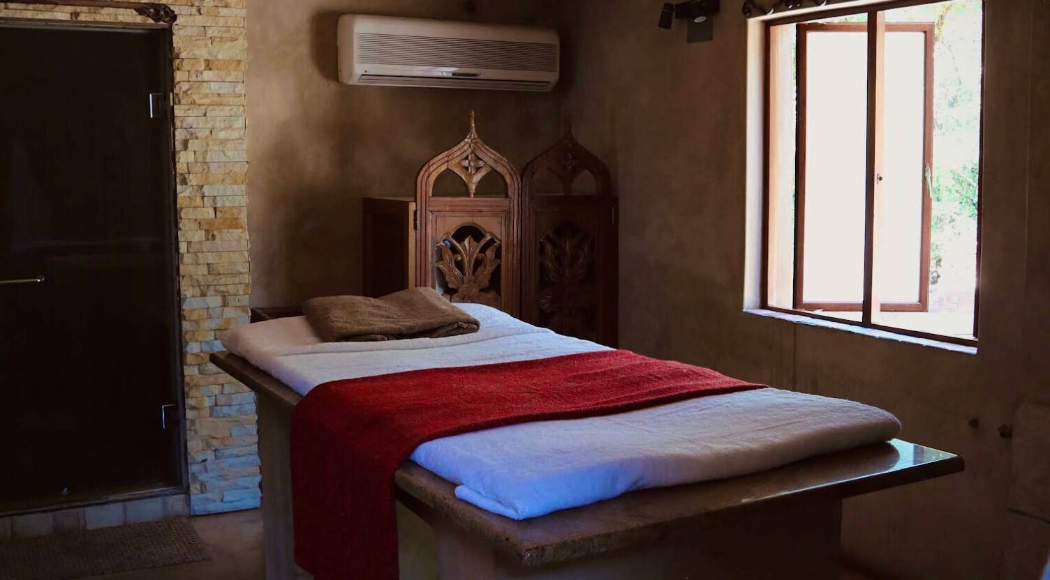 Cozy massage room at Bohemian Wellness & Spa, Pretoria, Gauteng, ZA with stone walls and a red blanket.