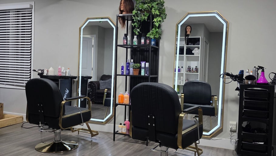 Interior moderno del salón Jackeline’s Hair en Calgary, Alberta, CA con sillas negras y espejos iluminados.