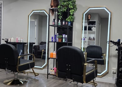 Interior moderno del salón Jackeline’s Hair en Calgary, Alberta, CA con sillas negras y espejos iluminados.