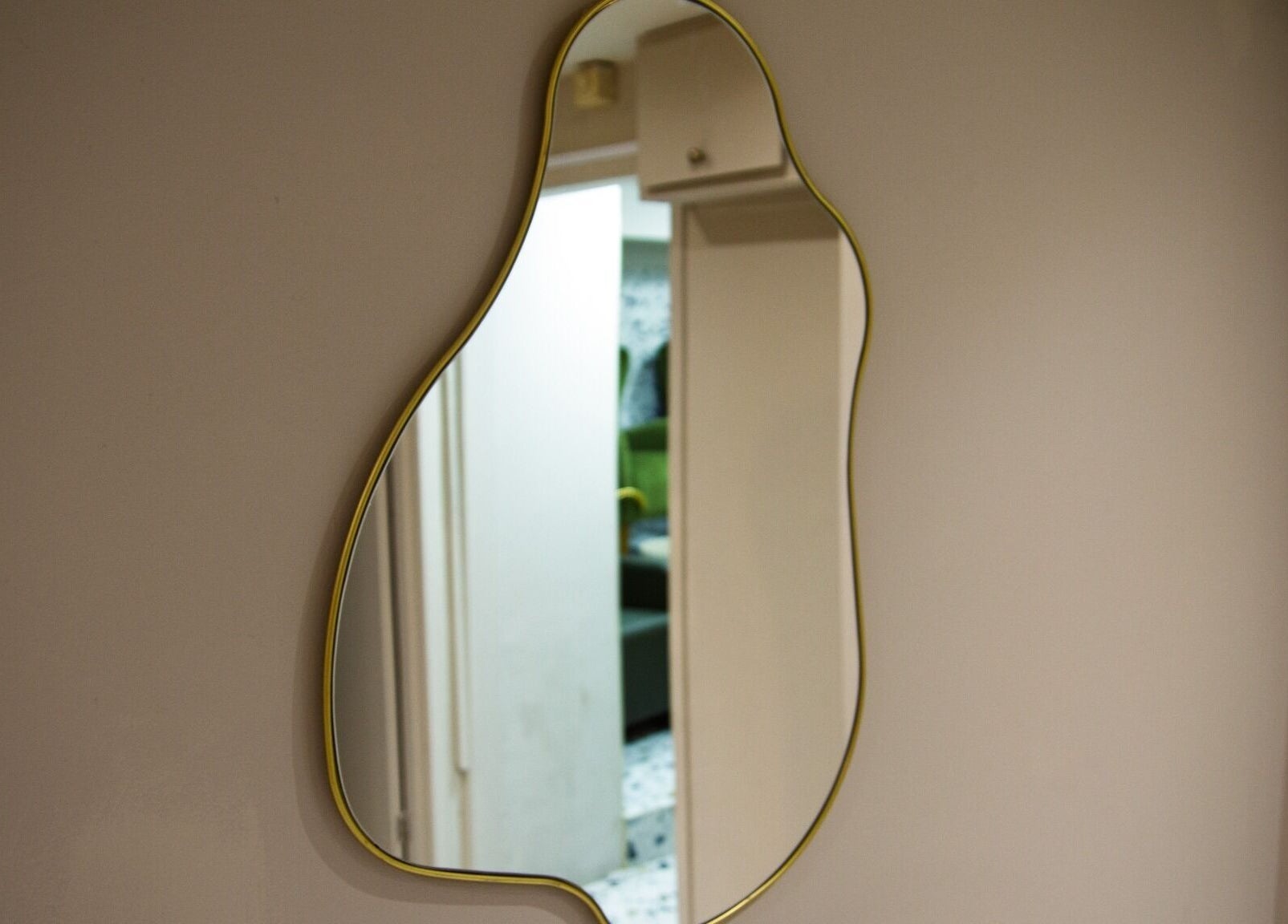 Unique curvy mirror on wall at Flow, London, England, GB, reflecting interior space.