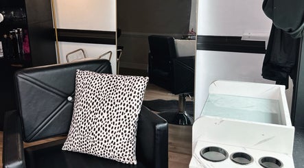 Eleventh Hour Hair in Gainesville, Georgia showcases modern black salon chair with a chic patterned pillow.
