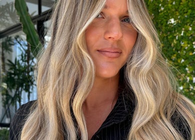 Woman with flowing blonde hair at VÉRAH, Yeppoon, Queensland, AU, showcasing natural beauty in lush setting.