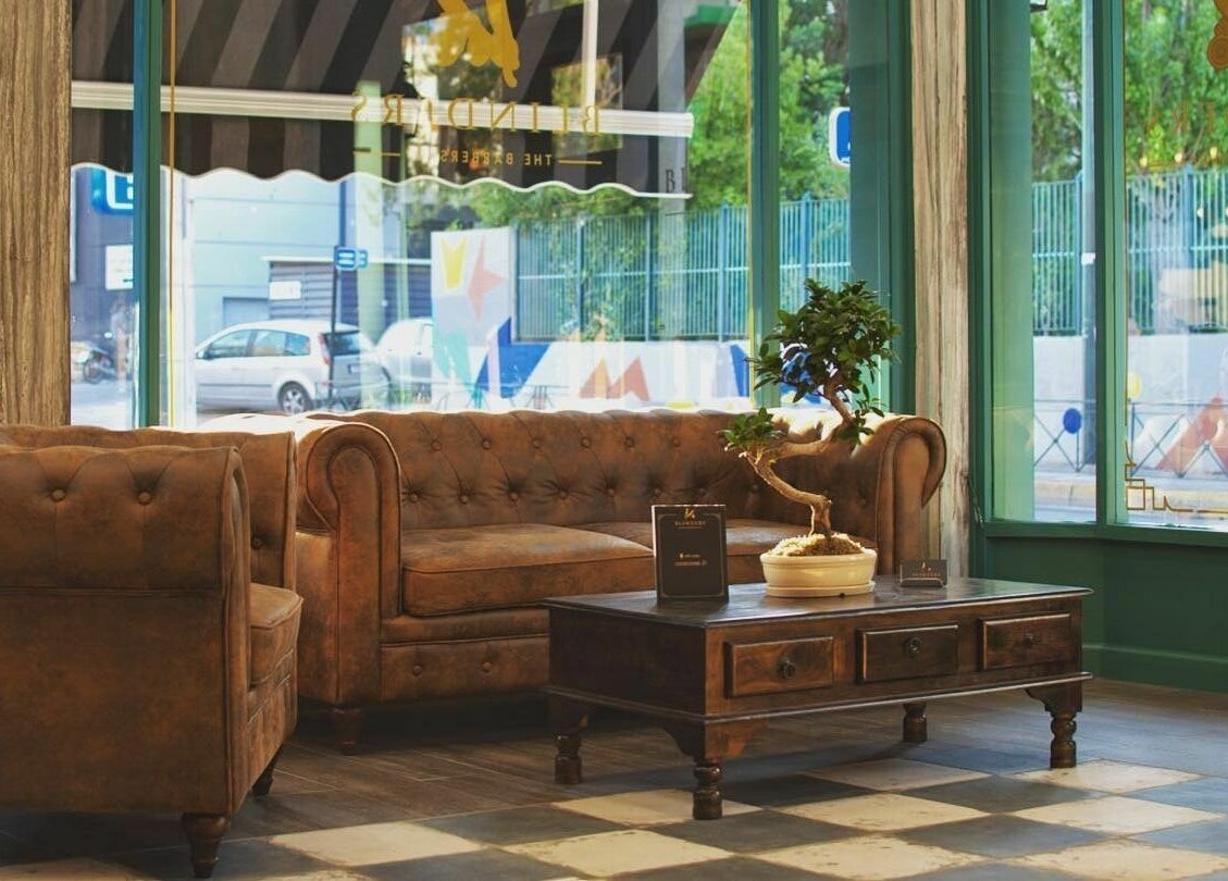 Άνετο καθιστικό στη Blinders Barbershop, Αθήνα, GR με δερμάτινο καναπέ και ρουστίκ τραπεζάκι.
