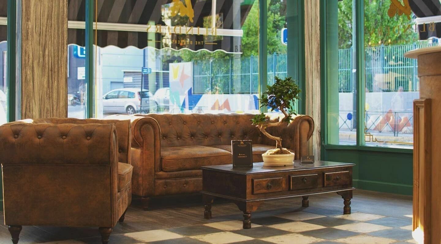 Άνετο καθιστικό στη Blinders Barbershop, Αθήνα, GR με δερμάτινο καναπέ και ρουστίκ τραπεζάκι.