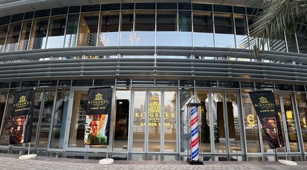 Front view of Kingsmen Barbershop in Dubai, Dubai, AE, showcasing modern glass facade and signage.
