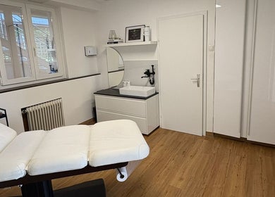 Moderner Behandlungsraum bei Brow Lash Care, Heimschuh, Steiermark, AT, mit weißem Interieur und Holzfußboden.