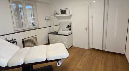 Moderner Behandlungsraum bei Brow Lash Care, Heimschuh, Steiermark, AT, mit weißem Interieur und Holzfußboden.