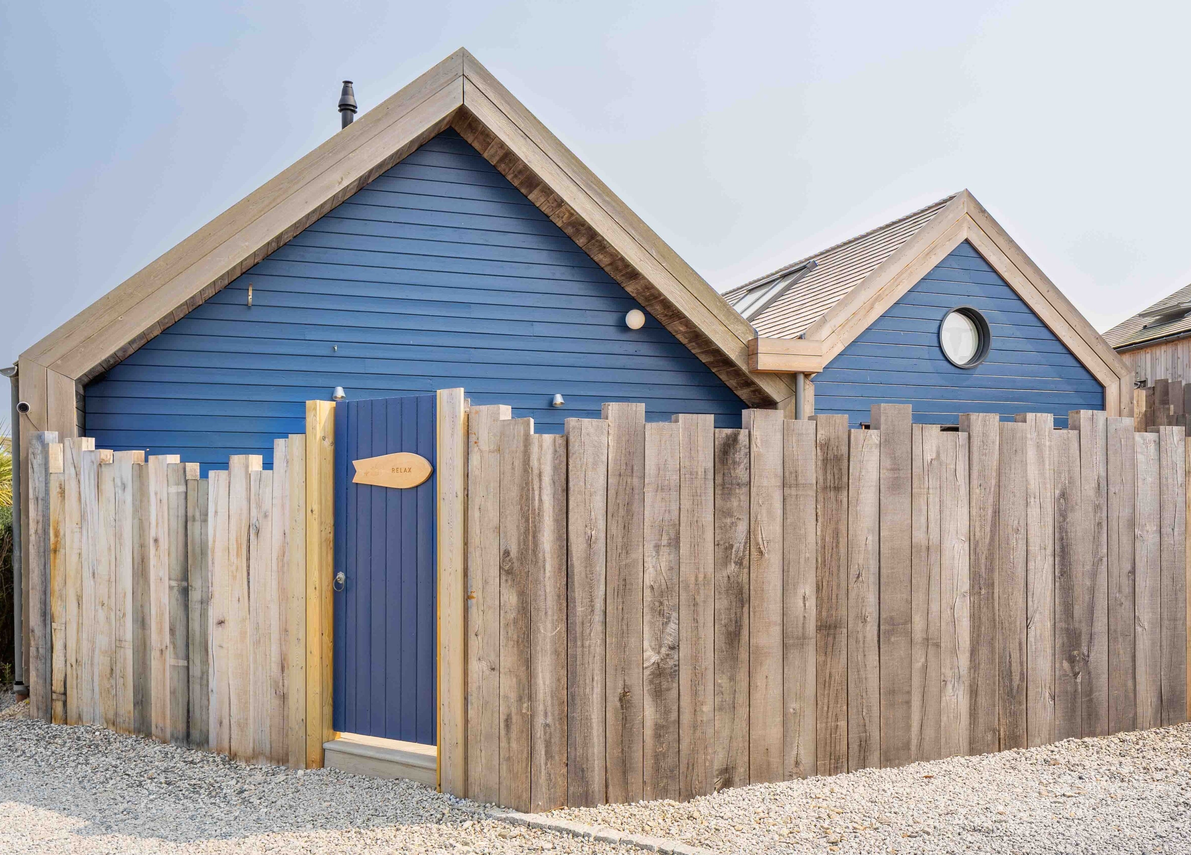 Charming blue cabin at Relax at Three Mile Beach, Gwithian, England, GB, enclosed by rustic wooden fences.