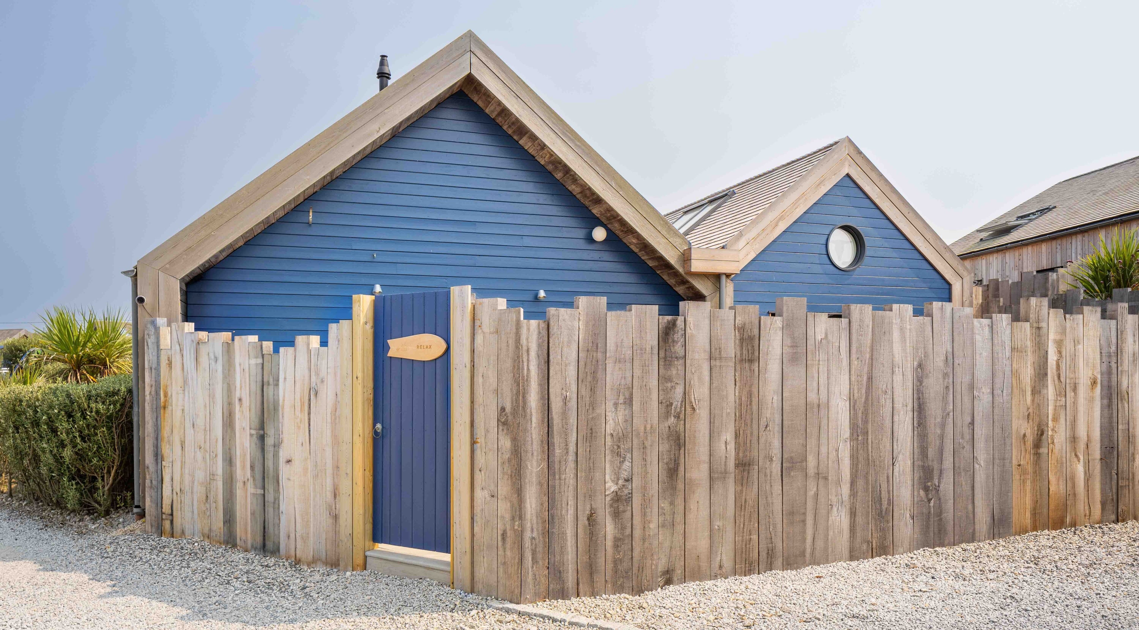 Charming blue cabin at Relax at Three Mile Beach, Gwithian, England, GB, enclosed by rustic wooden fences.