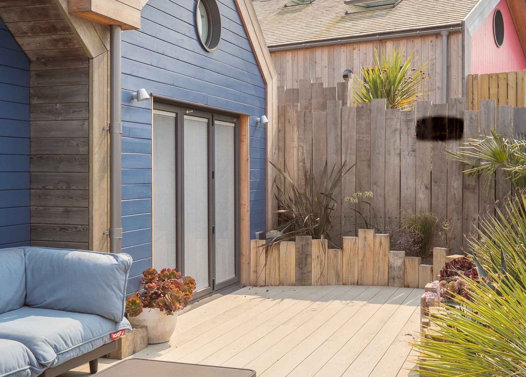 Relax at Three Mile Beach's inviting deck area in Gwithian, England, GB, featuring cozy seating and lush greenery.