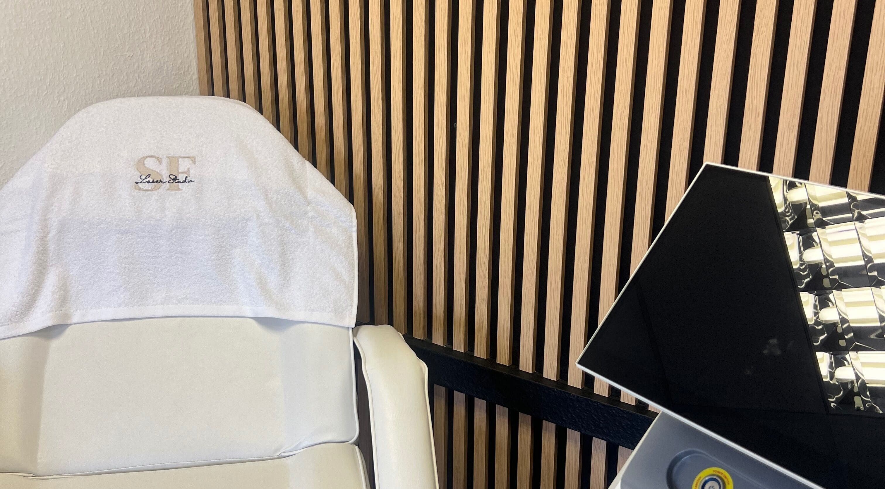 Modern treatment chair in SF LASER, Dereham, England, GB with striped wooden wall and sleek equipment.