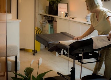 Therapist prepping massage table at Dzen Clinic, Crossgates, Scotland, GB, ensuring a calm wellness space.