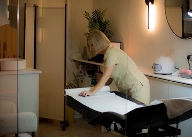 Therapist preparing a treatment table at Dzen Clinic, Crossgates, Scotland, GB, creating a calming atmosphere.