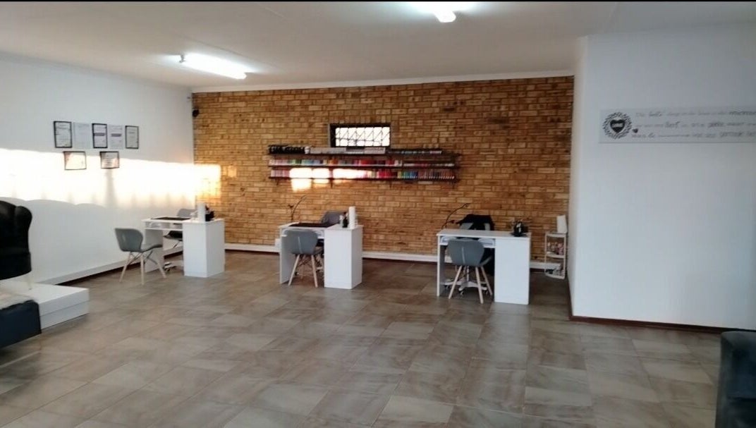 Modern salon interior at Bare & Polished, Westonaria, Gauteng, ZA, featuring sleek workstations and brick walls.