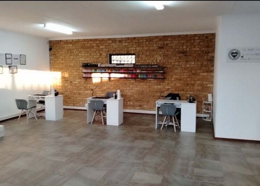 Modern salon interior at Bare & Polished, Westonaria, Gauteng, ZA, featuring sleek workstations and brick walls.