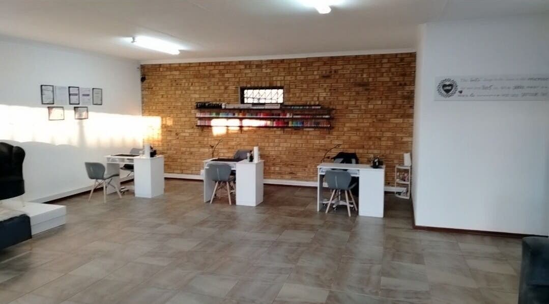Modern salon interior at Bare & Polished, Westonaria, Gauteng, ZA, featuring sleek workstations and brick walls.