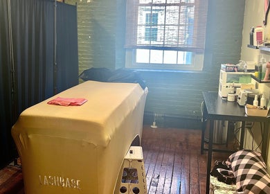 Cozy treatment room at Rosy Cheeks Beauty Studio in Biddeford, Maine, US, featuring a massage table and decor.