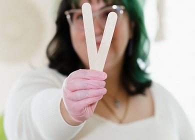Aesthetician holding waxing sticks at Rosy Cheeks Beauty Studio, Biddeford, Maine, US.