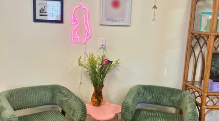 Cozy waiting area with green chairs and neon art at Rosy Cheeks Beauty Studio, Biddeford, Maine, US.