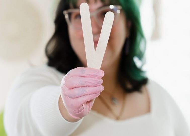 Professional holding waxing sticks at Rosy Cheeks Beauty Studio, Biddeford, Maine, US.