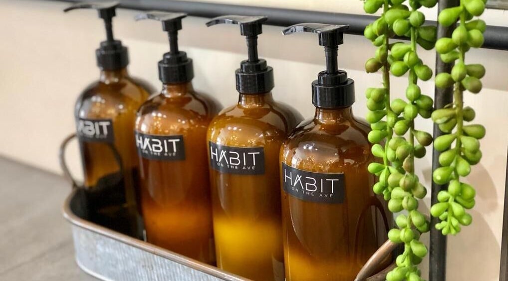 Amber bottles with Habit on the Ave labels, showcasing elegant style at Saint Michael, BB.