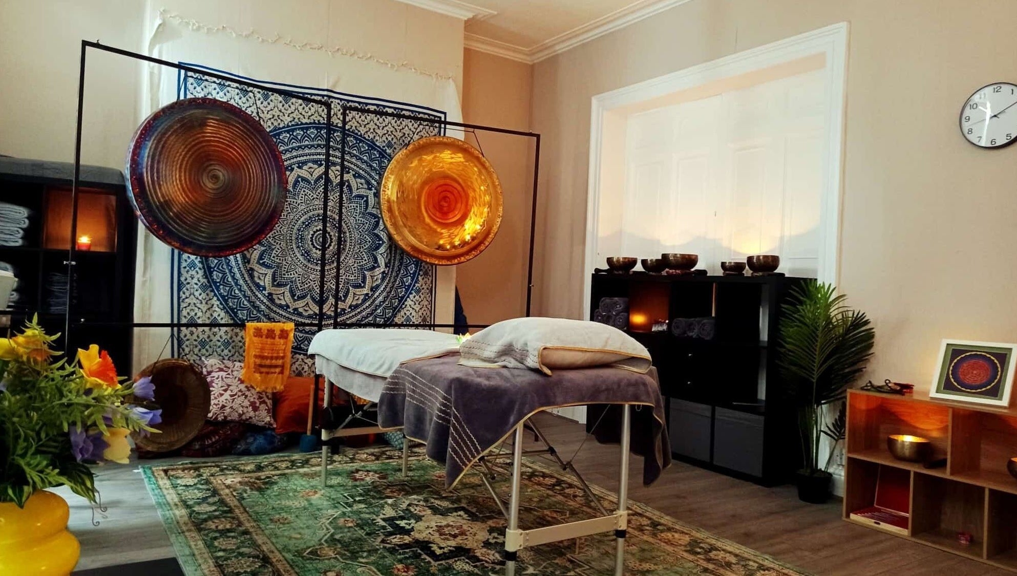 Tranquil therapy room at Dublin Healing, Dublin, County Dublin, IE, with gongs, flowers, and a therapy bed.
