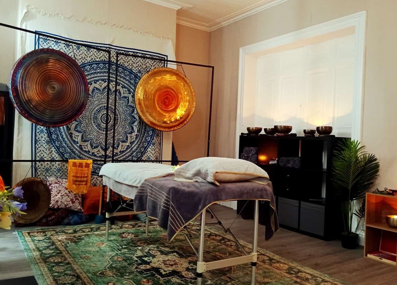 Tranquil therapy room at Dublin Healing, Dublin, County Dublin, IE, with gongs, flowers, and a therapy bed.