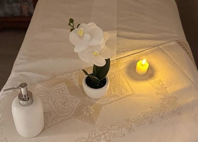 Tranquil massage table setup at Malai Thai North Finchley in London, England, GB with candlelight and a white orchid.