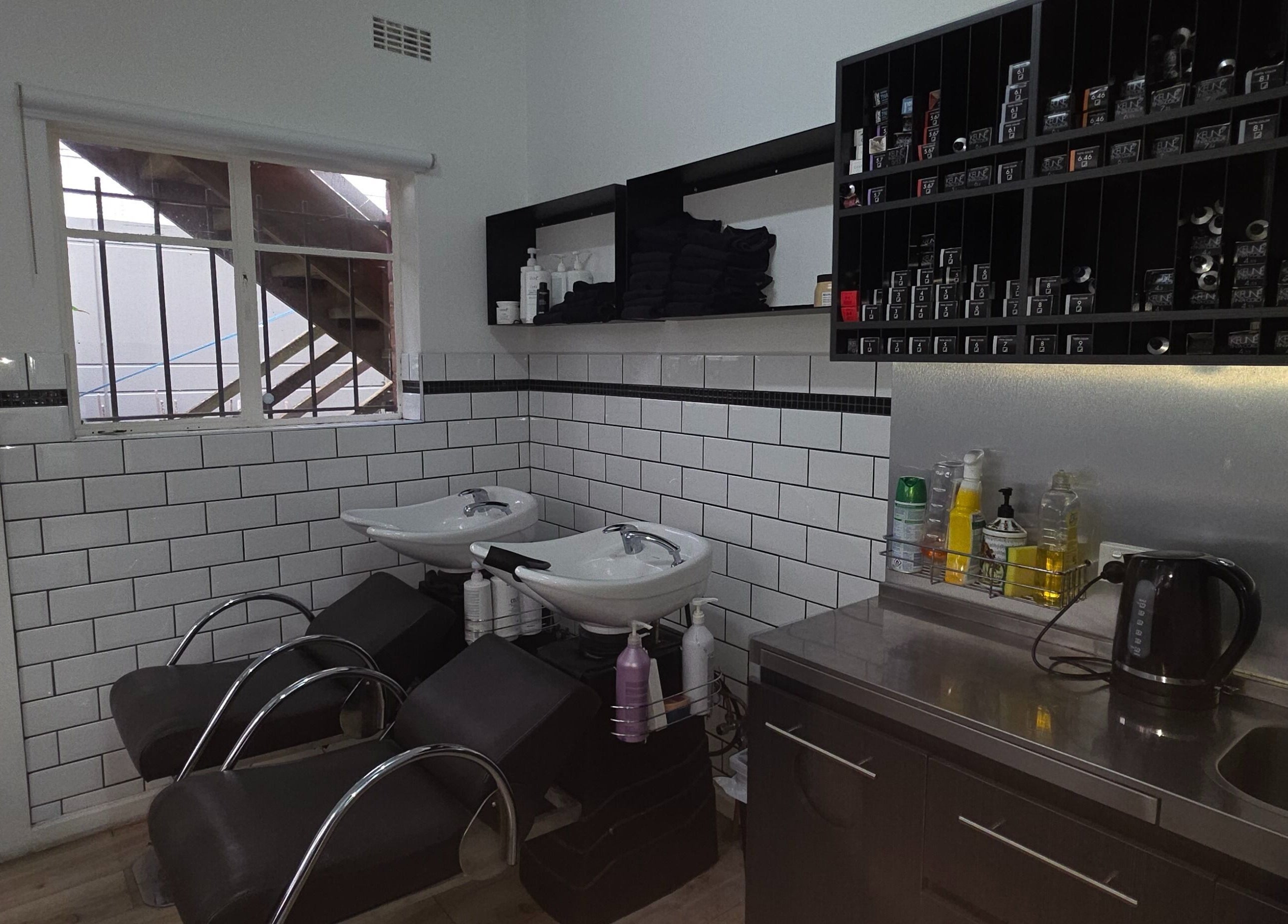 Modern shampoo area at Madu's Creation, Melbourne, Victoria, AU, featuring sleek chairs and tiled walls.