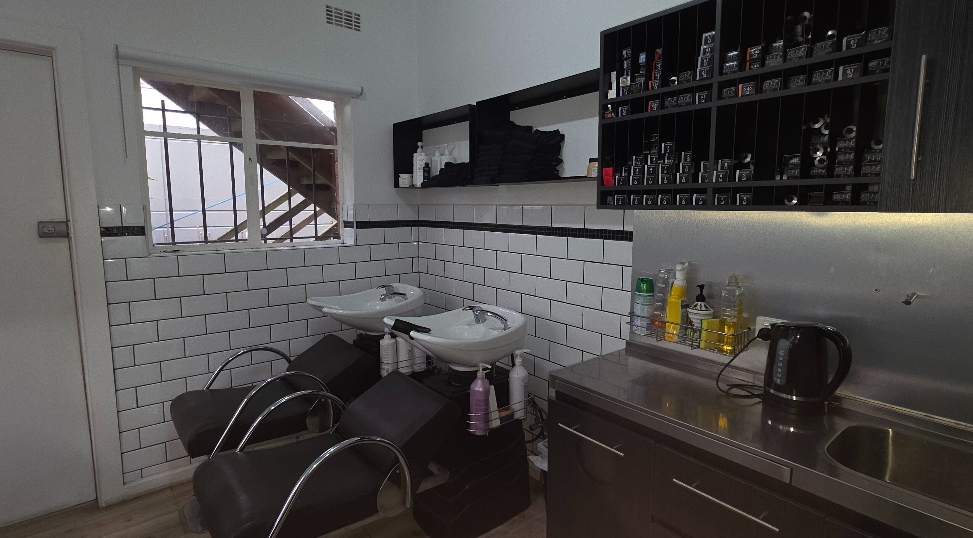 Modern shampoo area at Madu's Creation, Melbourne, Victoria, AU, featuring sleek chairs and tiled walls.