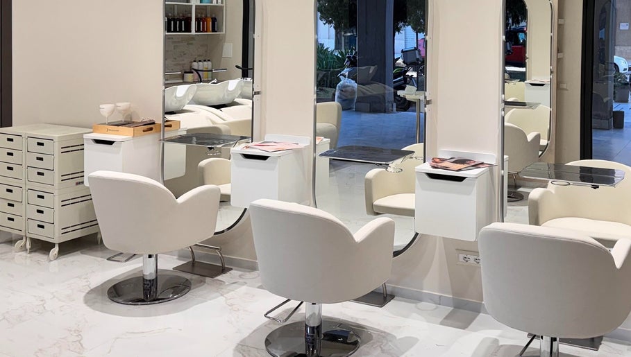 Interni eleganti di Enza Costantino Salon Beauty a Carlentini Nord, Sicilia, IT con sedie bianche e specchi moderni.
