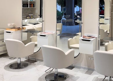 Interni eleganti di Enza Costantino Salon Beauty a Carlentini Nord, Sicilia, IT con sedie bianche e specchi moderni.