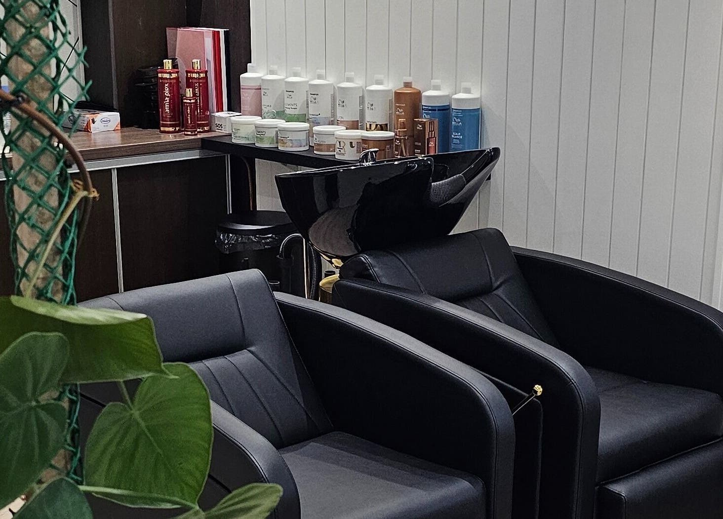 Intérieur de Studio 9 à La Possession, La Réunion avec fauteuils noirs et produits capillaires.