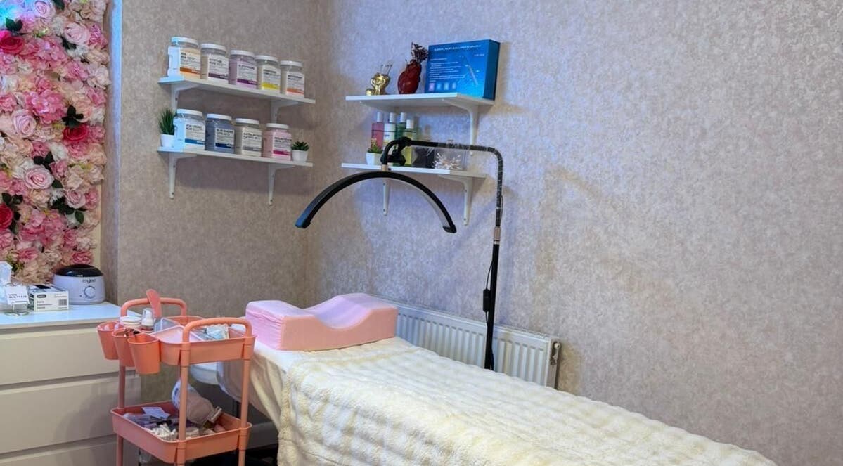 A cozy treatment room at Noor Beauty Lab, Enfield, England, GB with floral decor and skincare products.
