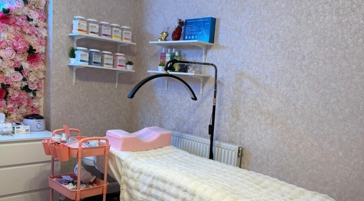 A cozy treatment room at Noor Beauty Lab, Enfield, England, GB with floral decor and skincare products.