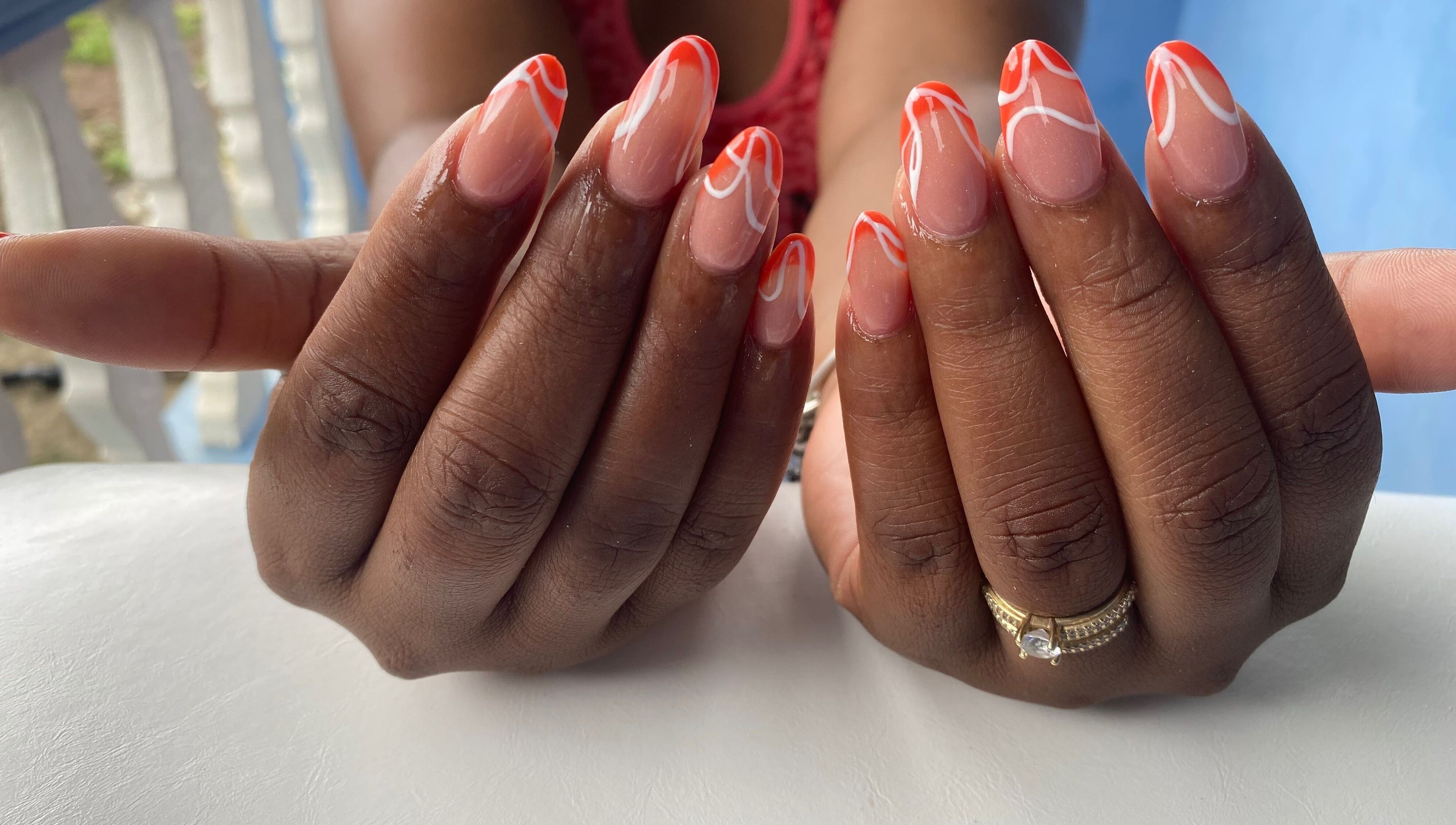 Stylish manicure with orange and white design at NailzbyTan, Biabou, Charlotte, VC.