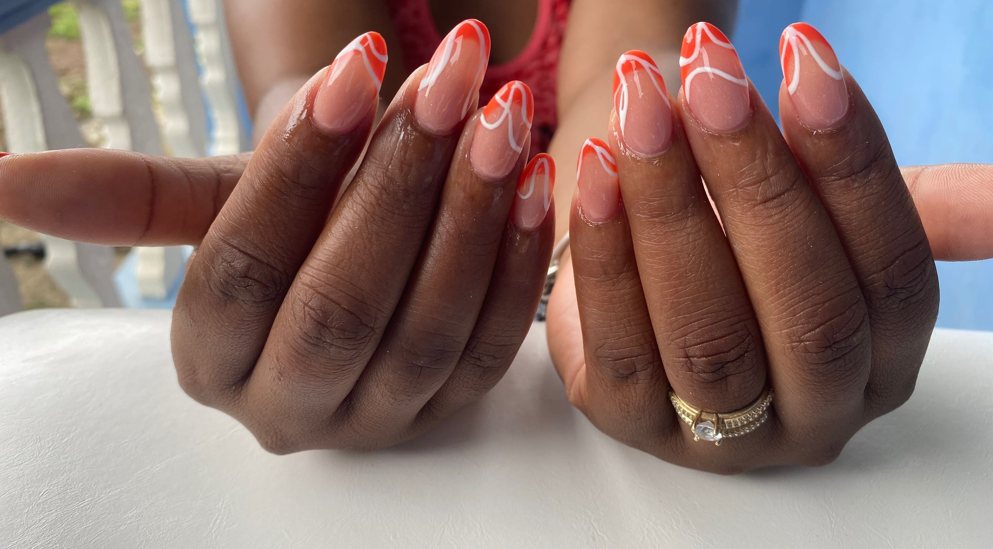 Stylish manicure with orange and white design at NailzbyTan, Biabou, Charlotte, VC.