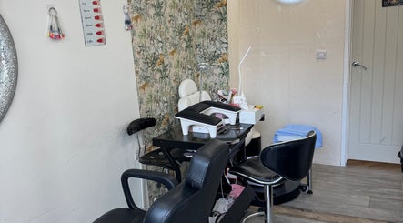 Stylish manicure station at Iconic Beauties in Hayes, England, GB with black chairs and floral wallpaper.