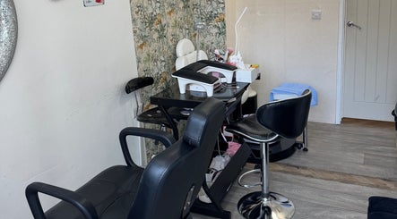 Modern salon interior at Iconic Beauties, Hayes, England, GB featuring stylish black leather chairs and floral decor.