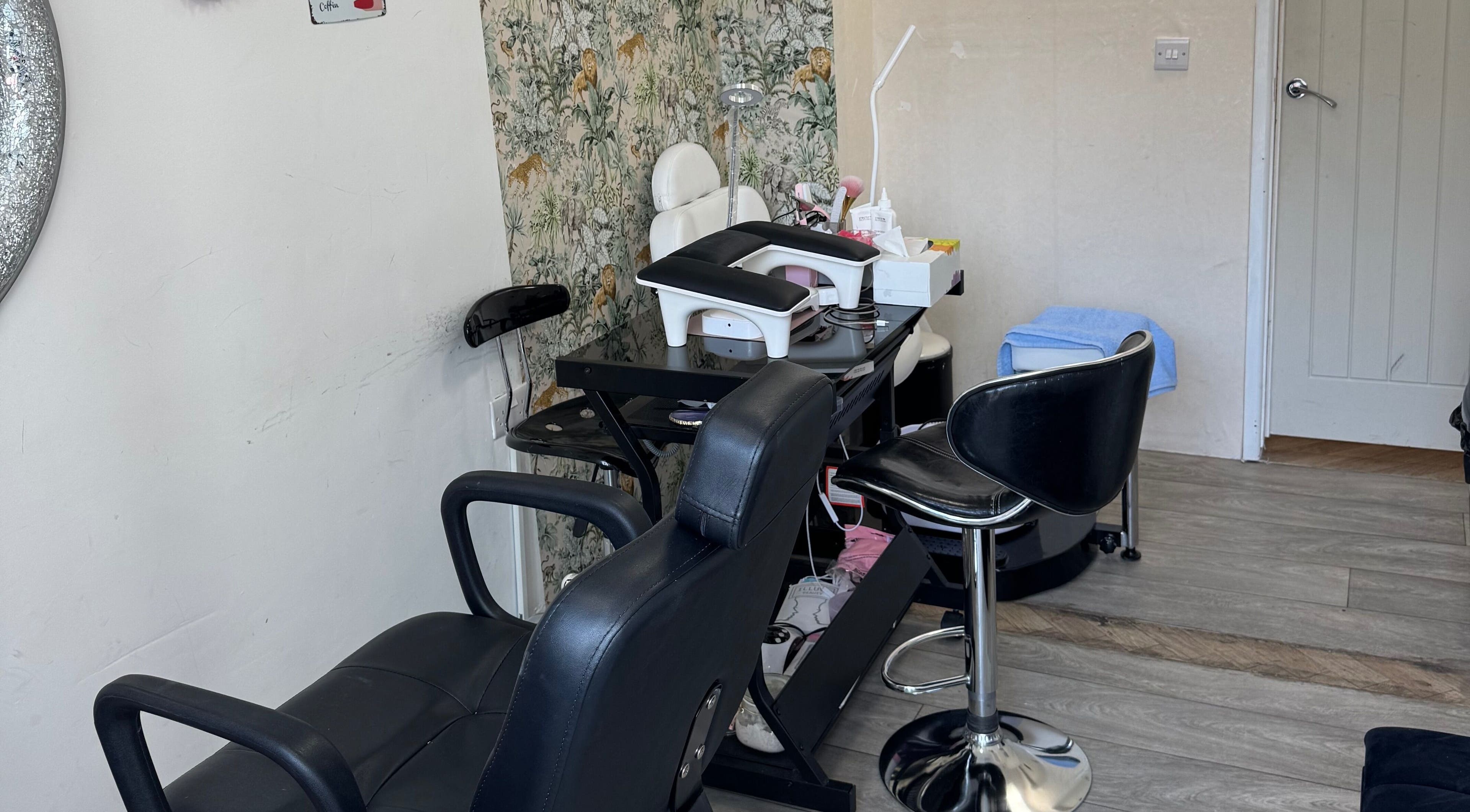 Modern salon interior at Iconic Beauties, Hayes, England, GB featuring stylish black leather chairs and floral decor.