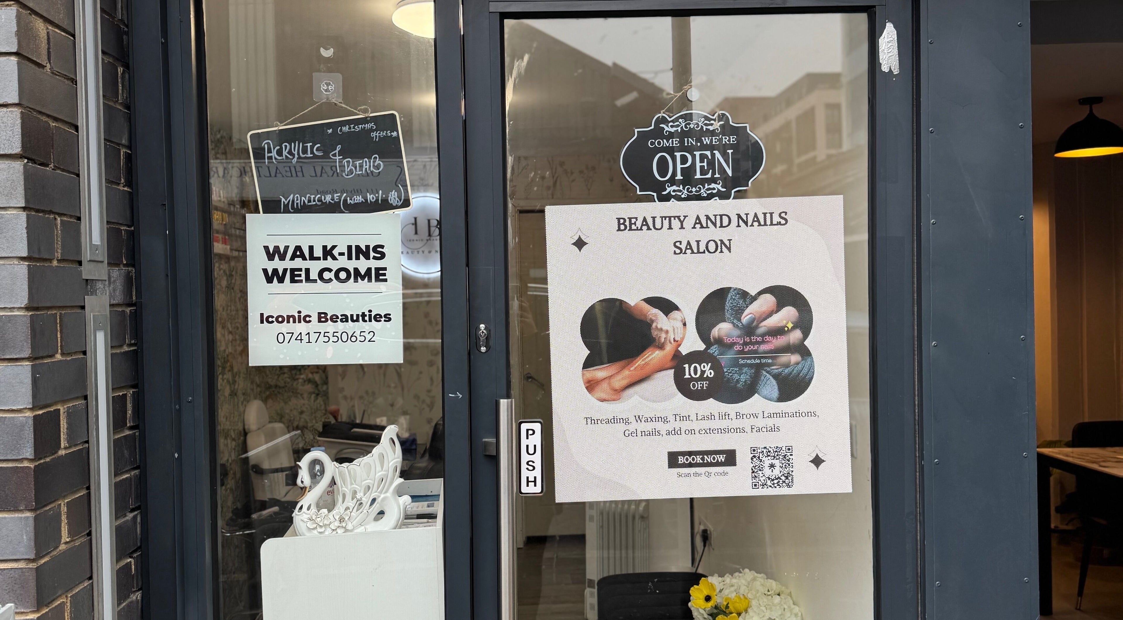 Entrance of Iconic Beauties in Hayes, England; beauty and nails salon with promotional signage.