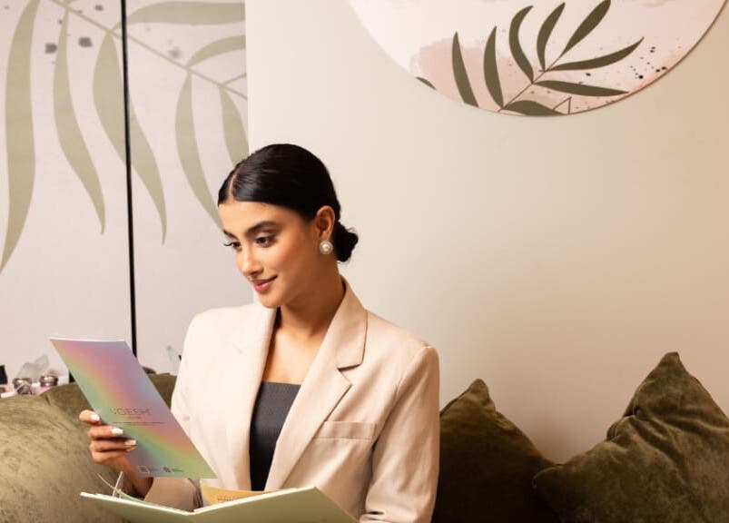 Woman reading brochure at MBS Nails Spa, Muscat, OM, with elegant decor.