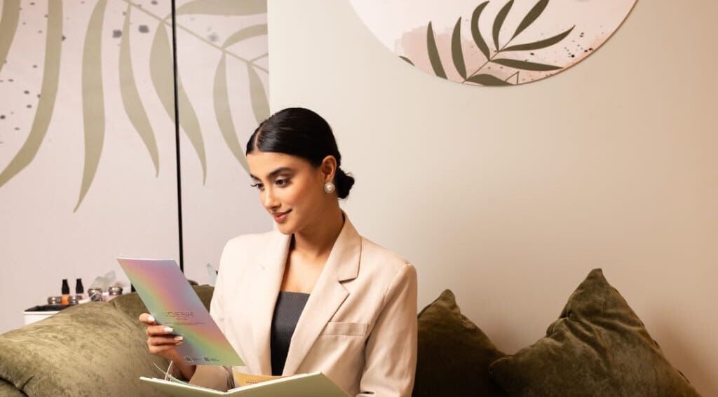 Woman reading brochure at MBS Nails Spa, Muscat, OM, with elegant decor.