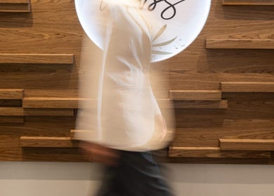 A person walking past the stylish wooden decor at MBS Nails Spa, Muscat, OM.
