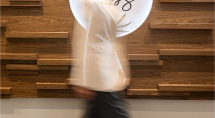 A person walking past the stylish wooden decor at MBS Nails Spa, Muscat, OM.