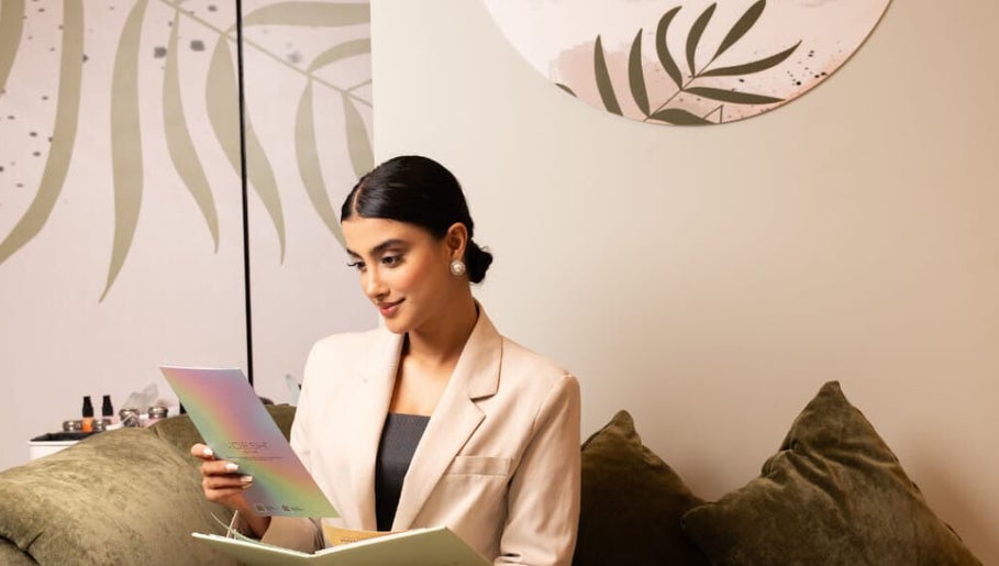 Woman reading a brochure at MBS Luxe Hair and Beauty, Muscat, OM in a serene setting.