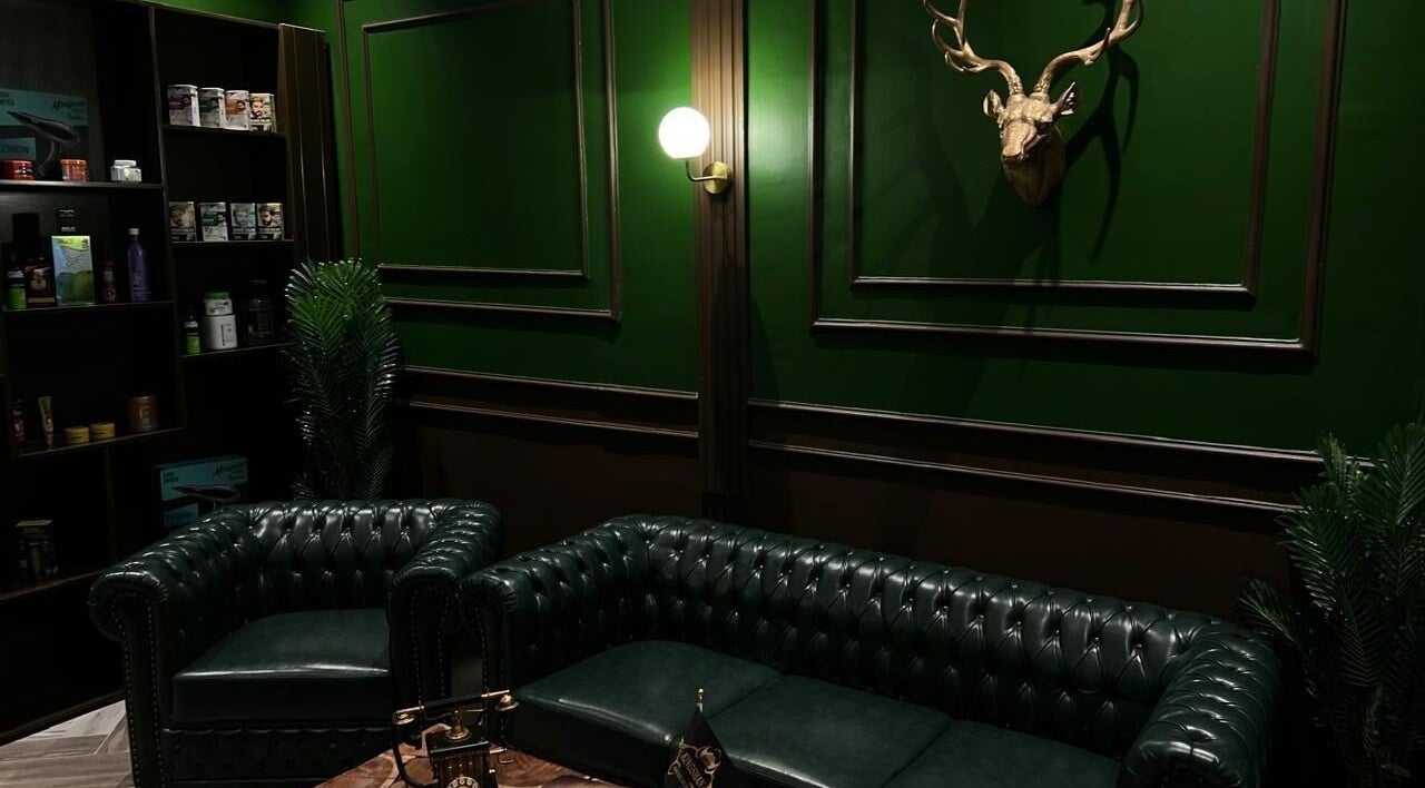 Elegant green interior of Kingsman Barbershop, Riyadh, Riyadh Province, SA with leather sofas and wall decor.