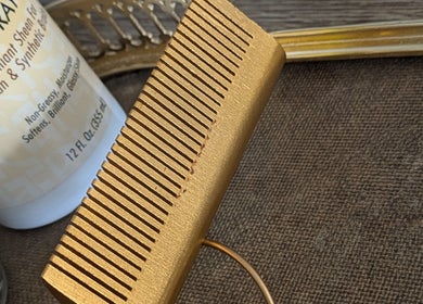 A golden comb and hair spray at Teya Hair, Mission, British Columbia, CA, showcasing premium hair care tools.