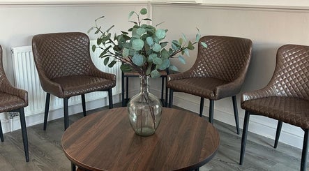 Chic waiting area at CK Beauty Studios, Ilkeston, England, GB with brown chairs and vase centerpiece.