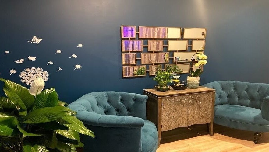 Cozy lounge at Miller Place, New York, US featuring teal armchairs, wall art, and vibrant plants.